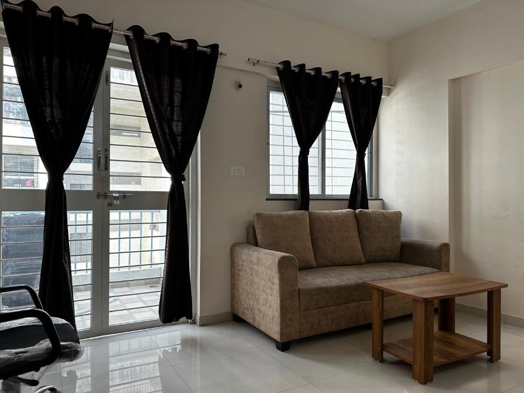 un soggiorno con sedia, tavolo e finestre di Blissful stays a Pune