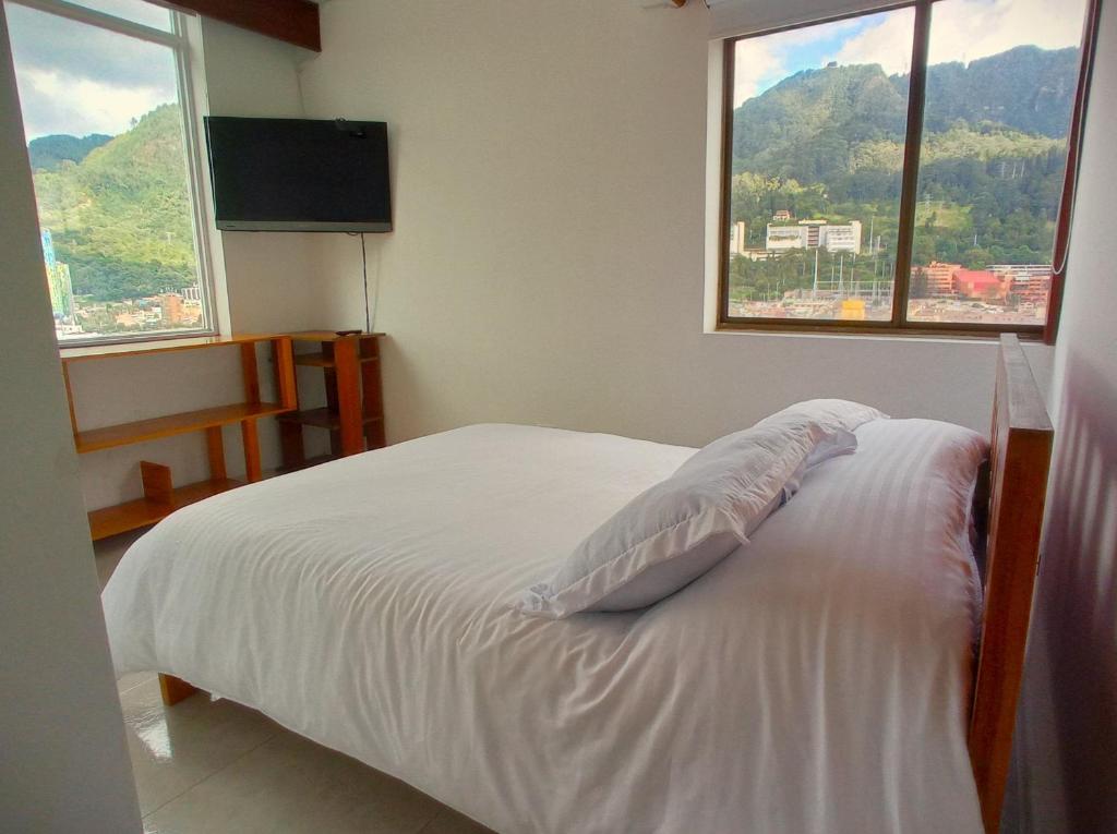 a white bed in a room with two windows at Apto - 1802B - Vista Única in Bogotá