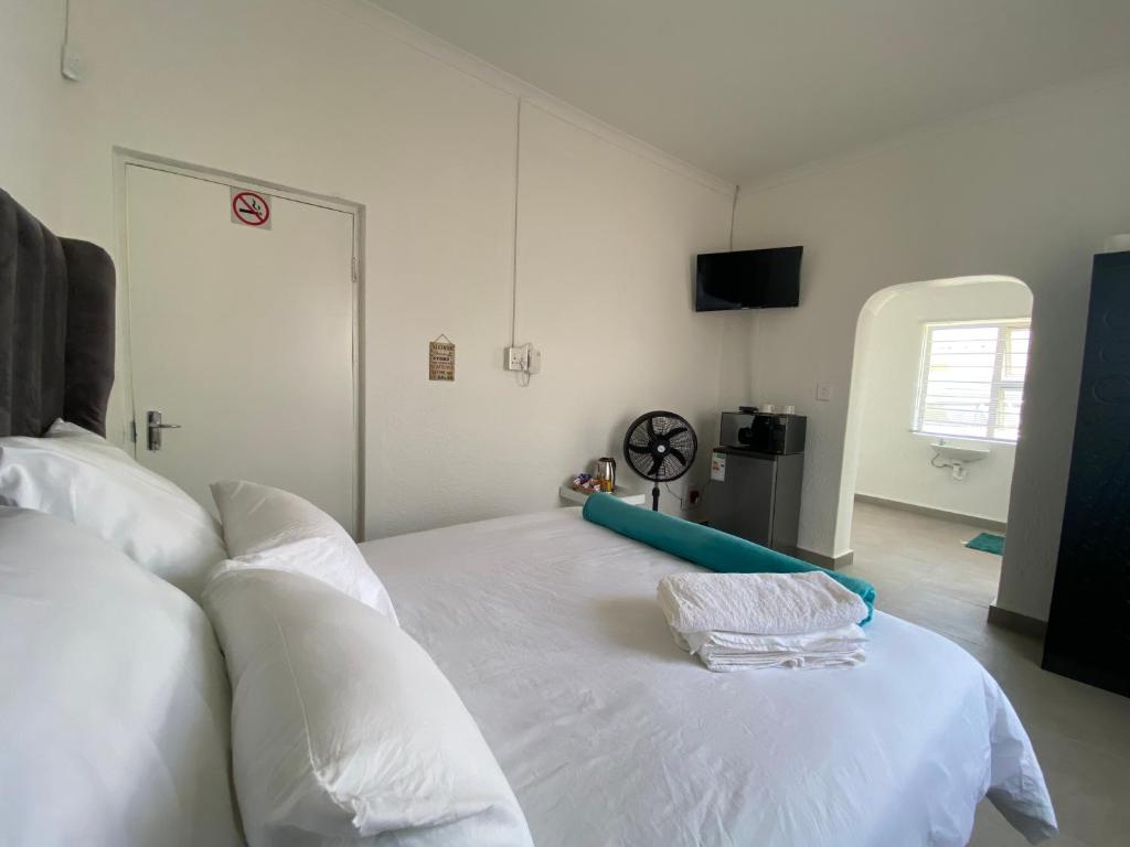 1 cama blanca grande en una habitación con reloj en No1 Guest House, en Ciudad del Cabo