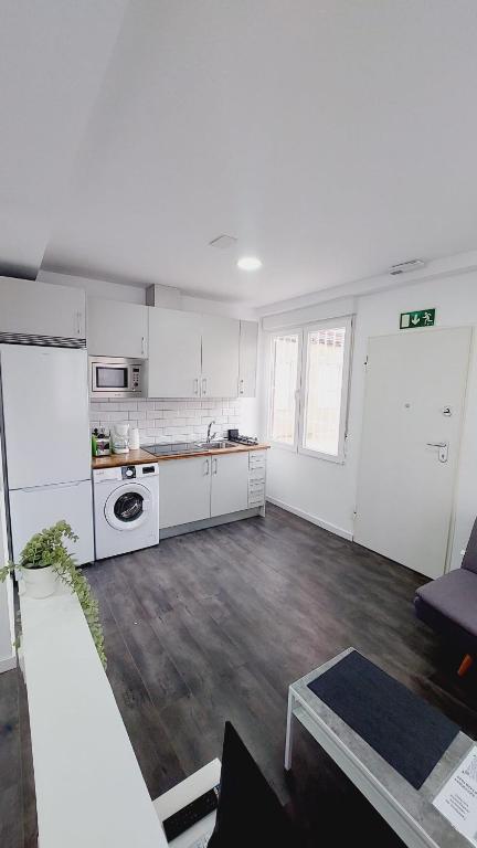 a large kitchen with white cabinets and a table at Lofts 4Towers - La Paz in Madrid