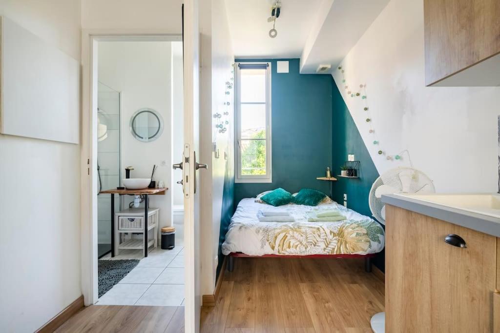 - une chambre avec des murs bleus, un lit et un lavabo dans l'établissement Le Vin Quatre, à Bergerac