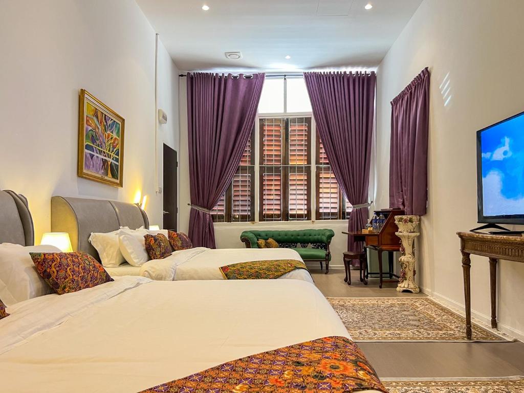 a hotel room with two beds and a flat screen tv at Peranakan Suites Georgetown in George Town