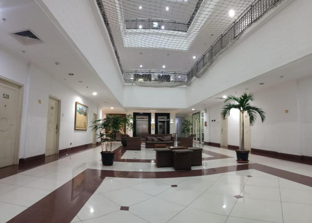 een lobby met banken en palmbomen in een gebouw bij APARTMEN MTC MEGAMAS in Manado
