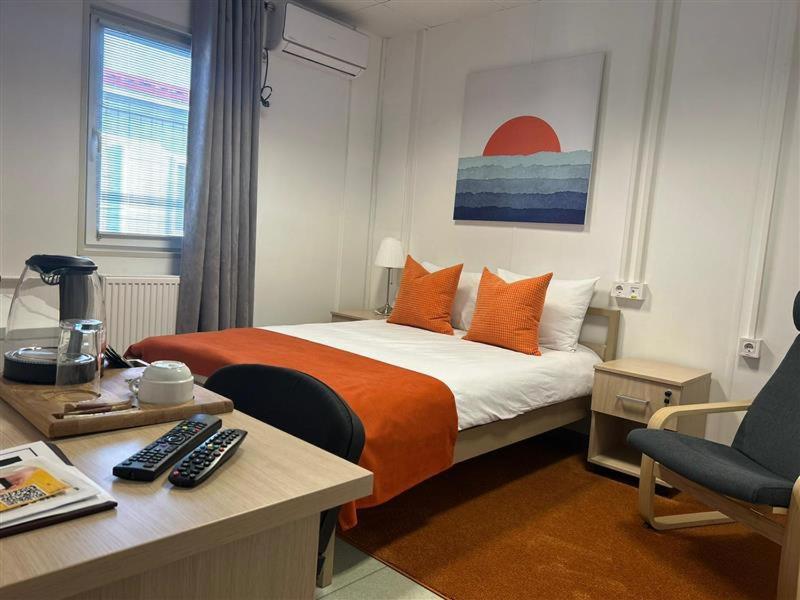 1 dormitorio con cama con almohadas de color naranja y escritorio en Birlik, en Tengiz