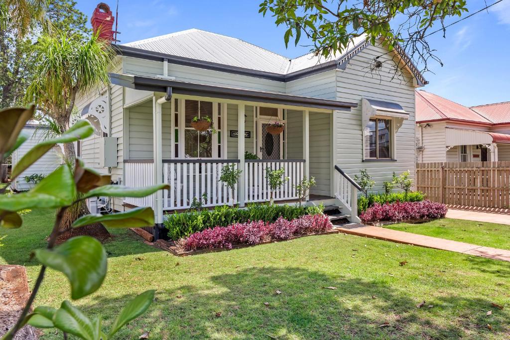 a house with a white fence in a yard at Ambiente Cottage - Pet and Family Friendly in Toowoomba