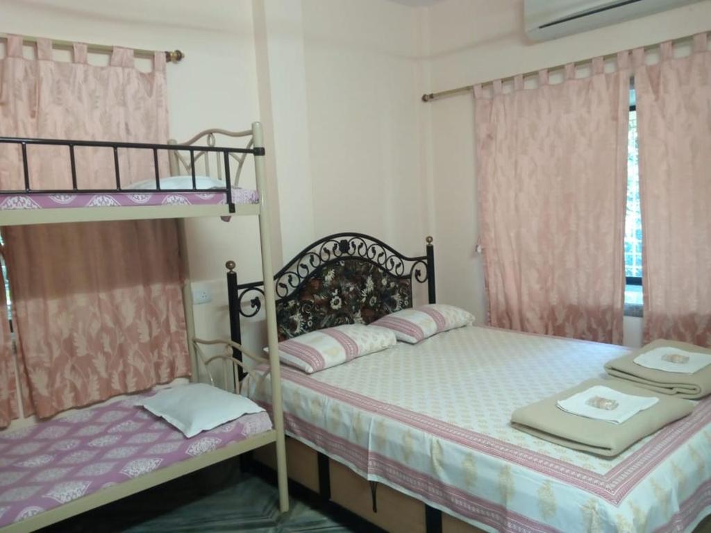 two bunk beds in a bedroom with pink curtains at Govindaashram in Bhogwe