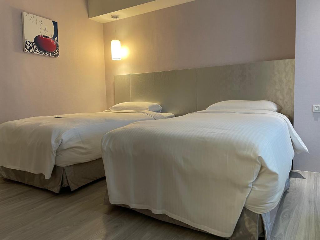 two beds in a hotel room with white sheets at 台北馥華商旅 松江館 in Taipei
