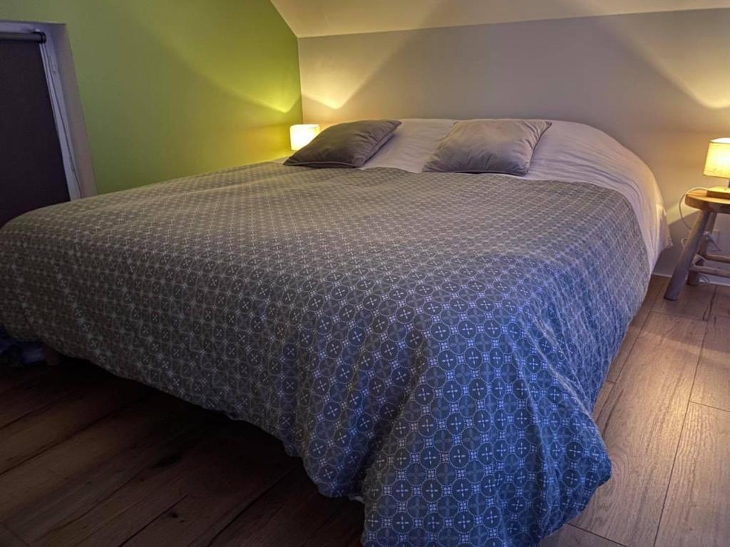 łóżko z niebiesko-białą kołdrą w sypialni w obiekcie La Suite ( chambre d’hôtes ) w mieście Aire-sur-la-Lys
