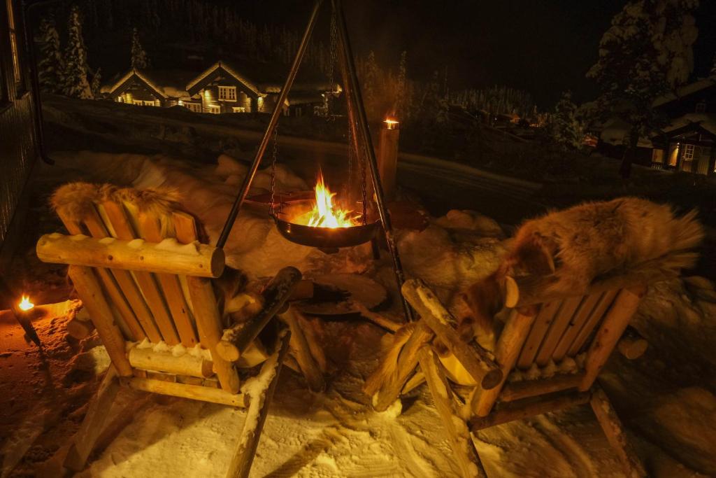 a fire pit with two chairs in the snow at night at Gausta Lodge med 6 sengeplasser i nærhet til Gaustatoppen in Gaustablikk