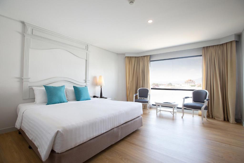 1 dormitorio con 1 cama grande con almohadas azules en CH Hotel en Chiang Mai