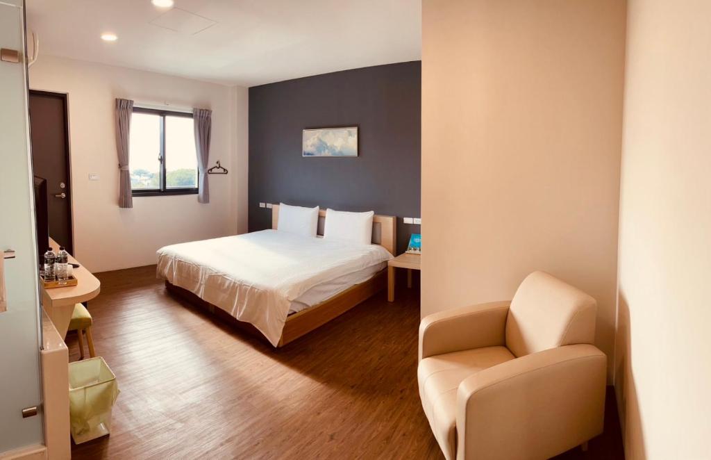 um quarto de hotel com uma cama e uma cadeira em Hospitality Hotel em Xiaoliuqiu
