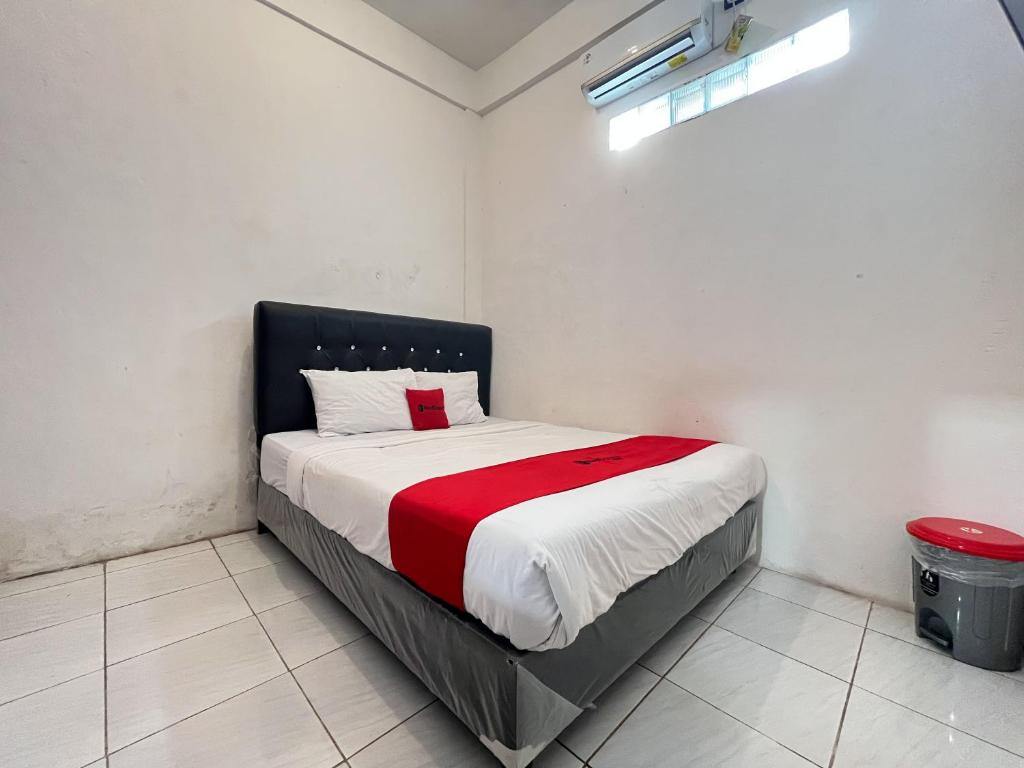 a bedroom with a bed with a red blanket on it at RedDoorz Syariah at Falisha UMY in Ngabean