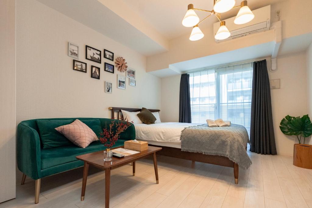 um quarto com um sofá verde, uma cama e uma janela em 谷町君ホテル　難波80 em Osaka