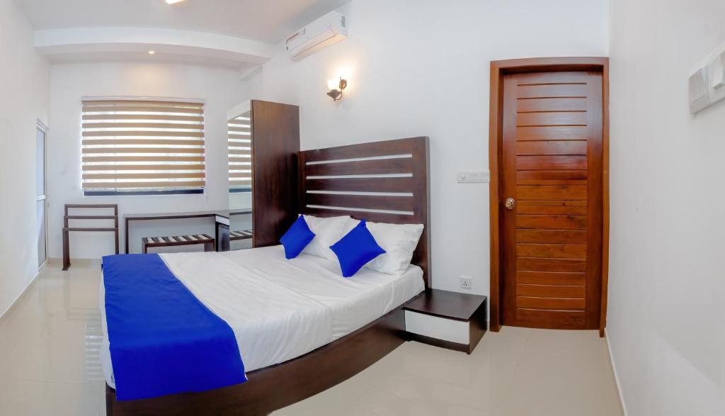 een slaapkamer met een bed en een houten deur bij Ceylanro Transit Villa in Negombo