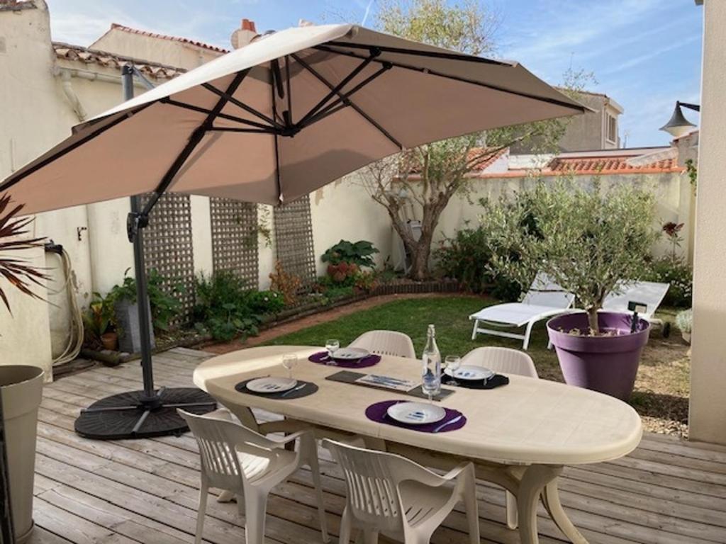 een tafel en stoelen onder een paraplu op een terras bij Maison Les Sables-d'Olonne, 3 pièces, 4 personnes - FR-1-422-42 in Les Sables-dʼOlonne