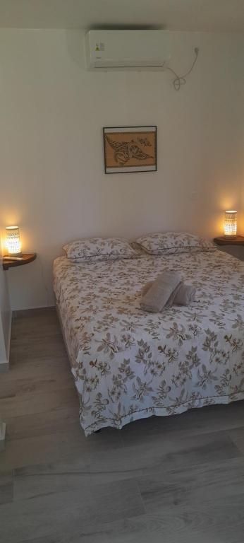 ein Bett in einem Schlafzimmer mit zwei Lampen und einer Bettdecke in der Unterkunft Bungalow Kahaia Lodge in Avatoru