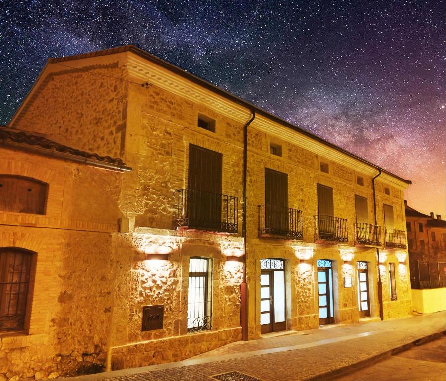 un edificio con un cielo estrellado detrás de él en Apartamentos LA CAÑADA DE OSMA en El Burgo de Osma