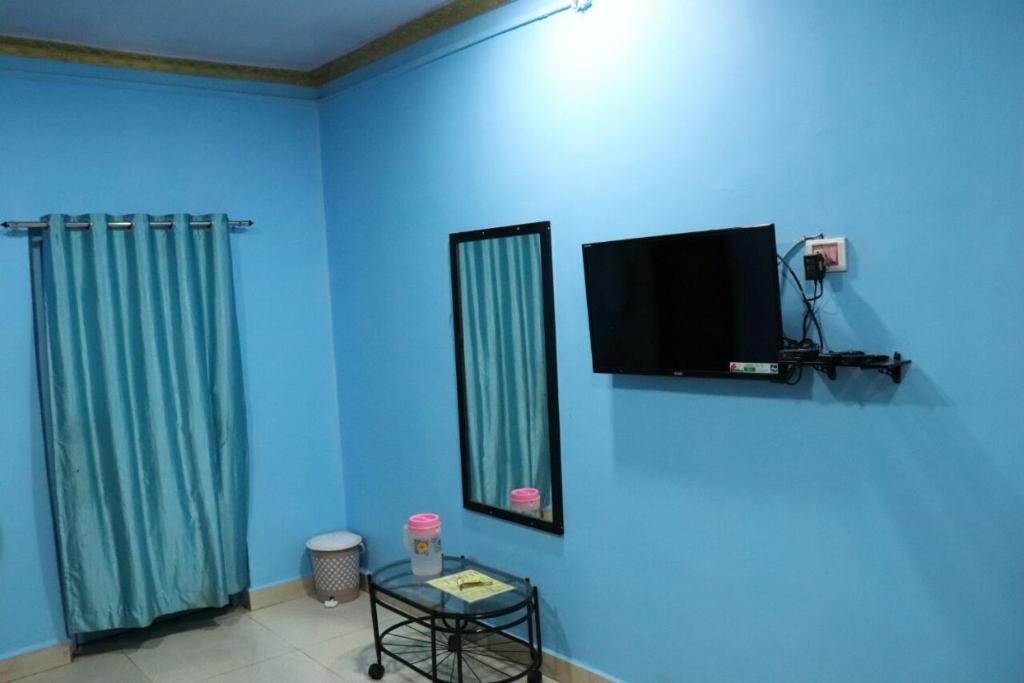 Habitación con pared azul y TV en la pared. en Ashirwad Cottage, en Matheran