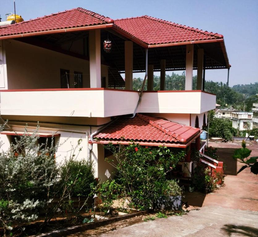 uma casa com um telhado vermelho e uma varanda em Nellakki Homestay em Madikeri