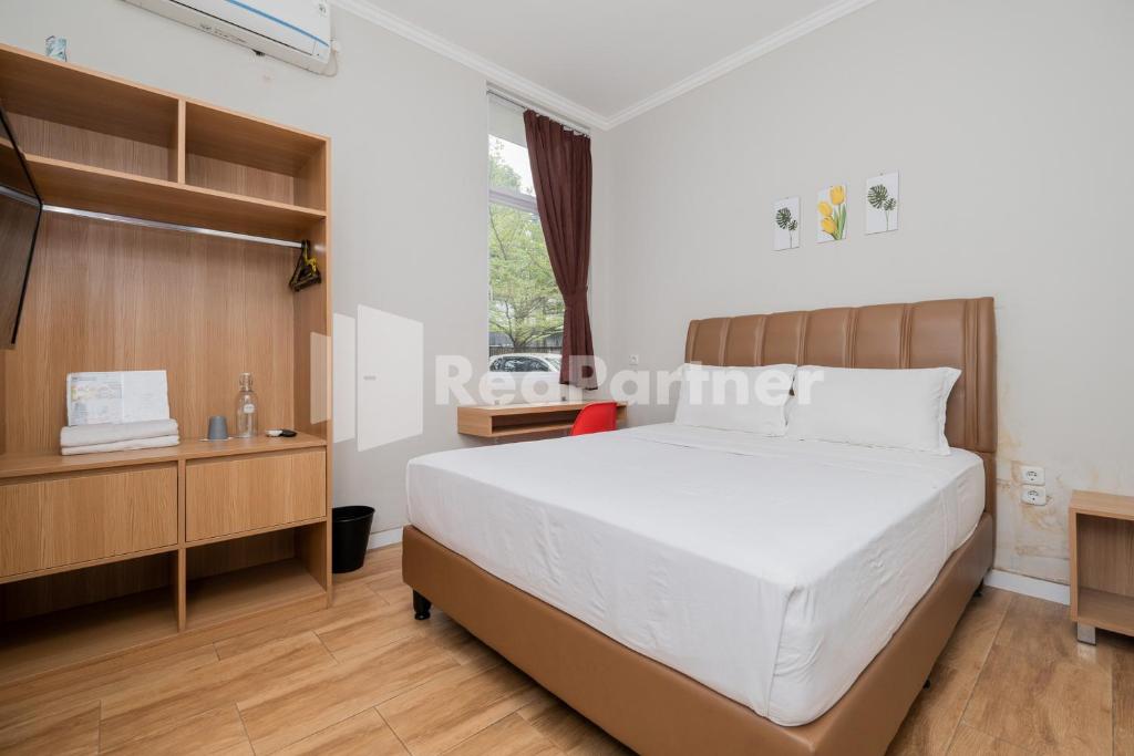 a bedroom with a large white bed and a window at Palm Eight Mitra RedDoorz in Jakarta
