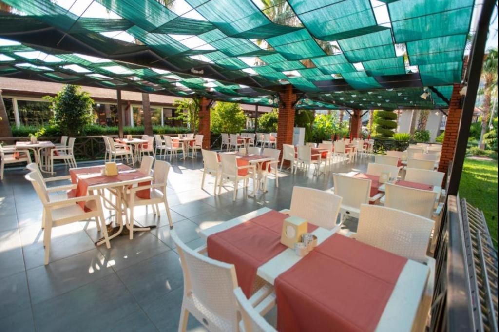 a restaurant with tables and chairs under a roof at MIR'AMOR GARDEN Resort Hotel-ALL INCLUSIVE in Antalya