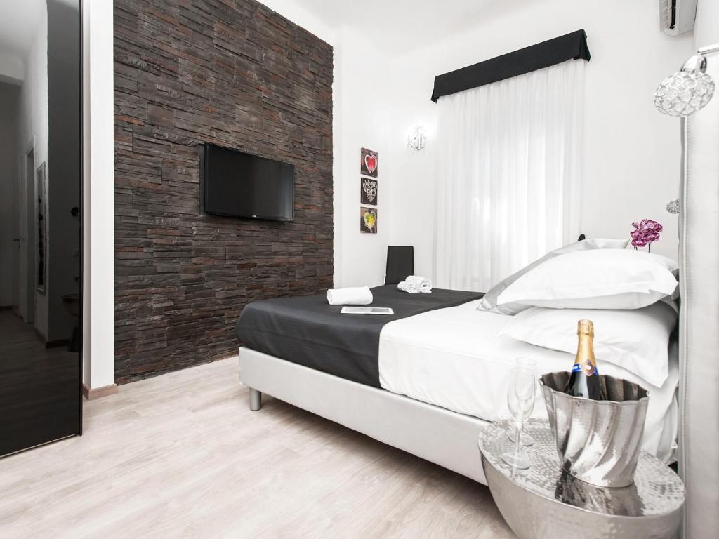 um quarto com uma cama e uma televisão numa parede de tijolos em Black Rooms Colosseo em Roma