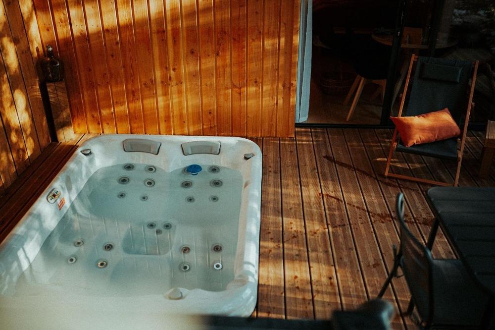 Aux Trois Chênes Lodge Spa في ميرْكو: حوض استحمام ساخن على سطح خشبي