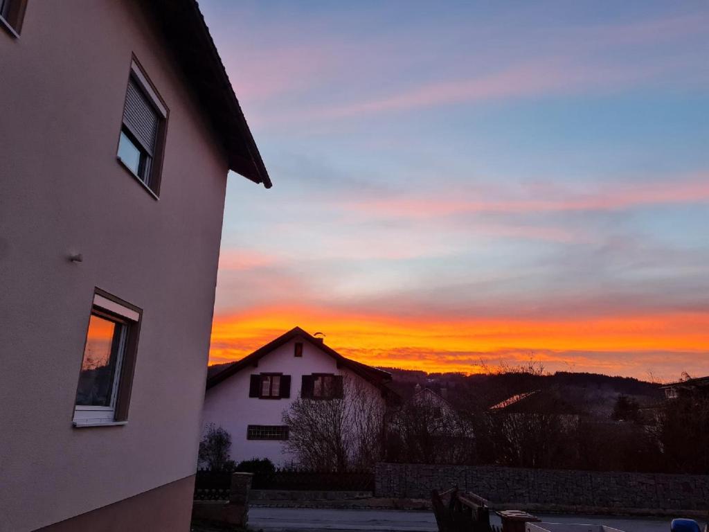 einen Sonnenuntergang hinter einem Haus und einem Gebäude in der Unterkunft Ferienhaus Falkenstein in Frauenau