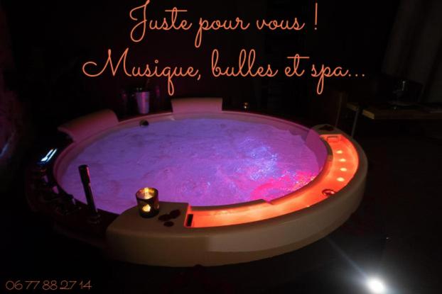 a jacuzzi tub in a room with a purple substance at LOVE Suites & SPA "Le Chai" avec lit rond in Médis