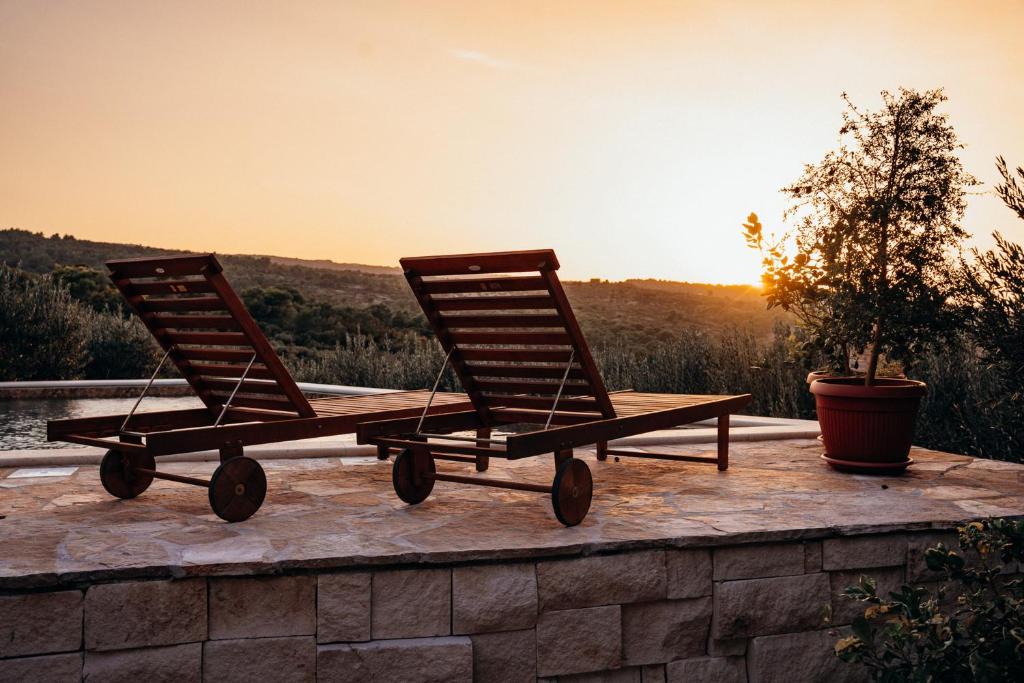 two rocking chairs sitting on a wall with the sunset at Villa Roza in Splitska