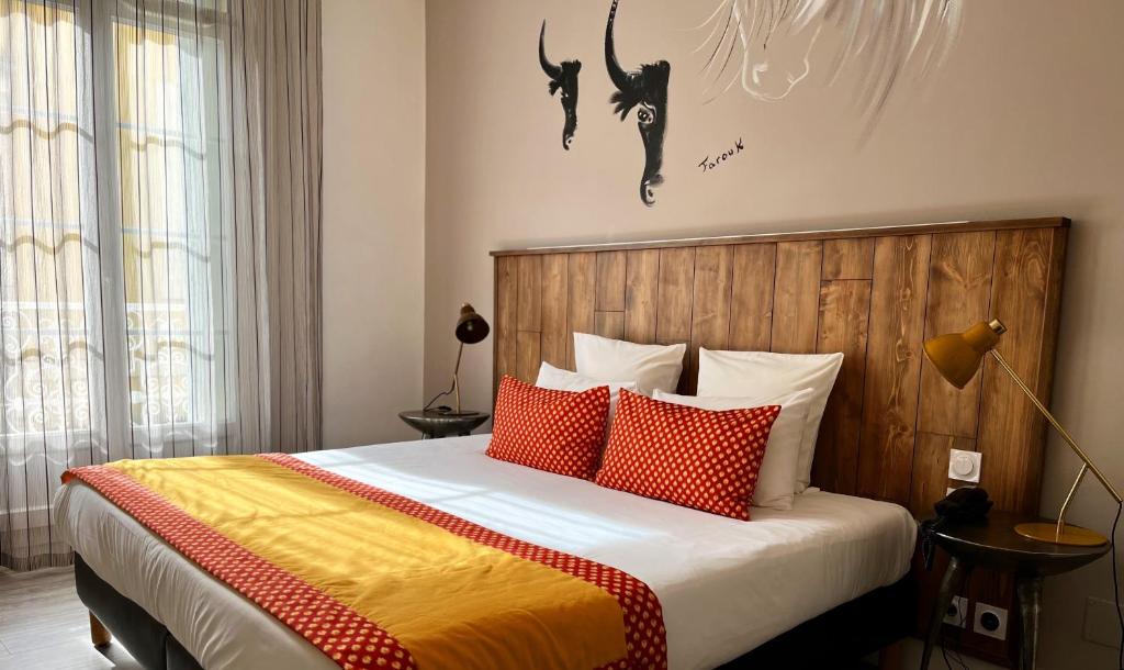 a bedroom with a bed with red and orange pillows at Hôtel Saint Louis in Aigues-Mortes