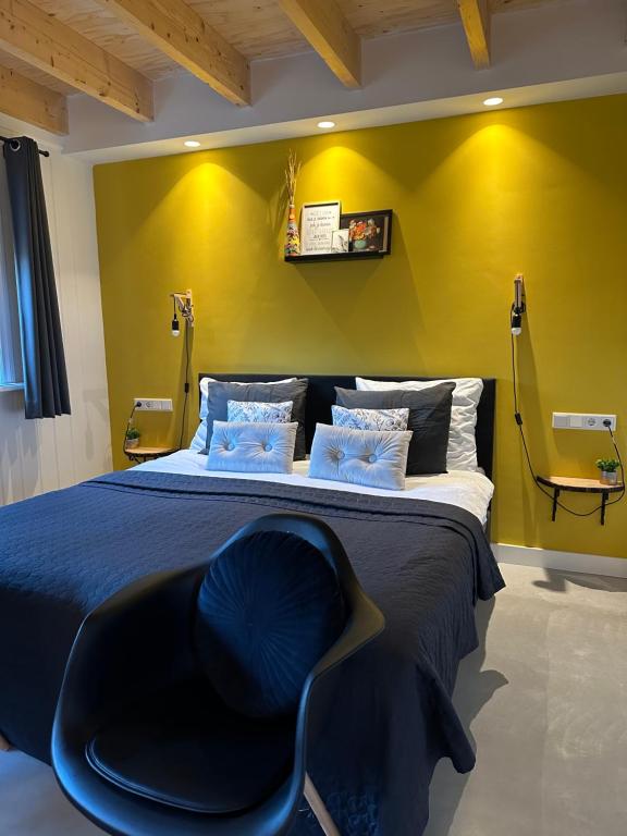een slaapkamer met een groot bed en een blauwe stoel bij La Fattoria Bed&breakfast in Venhuizen