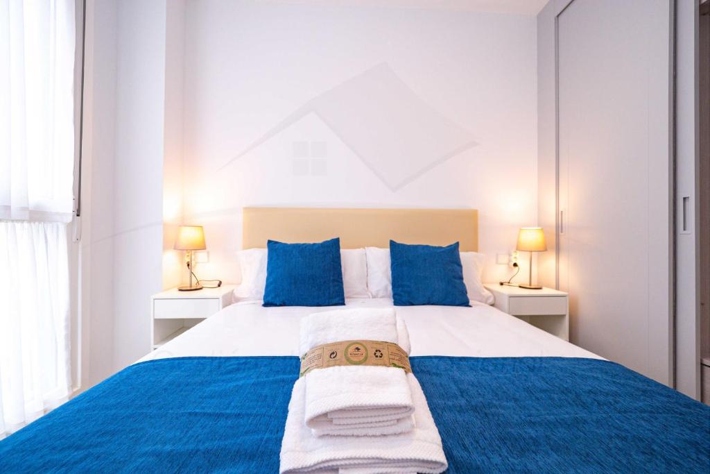 1 dormitorio con 1 cama azul y blanca y 2 lámparas en Casa Del Sol Apartamento en Gijón