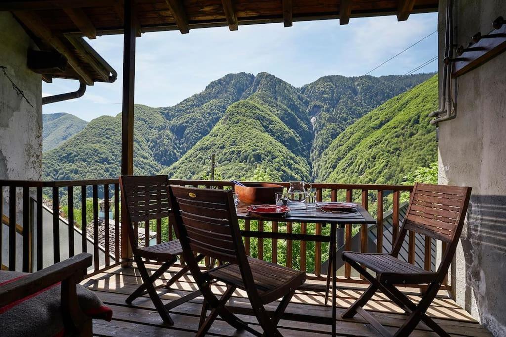 a table and chairs on a balcony with a view of mountains at Wild Valley Puro Ticino 1+2 in Valle Onsernone in Crana