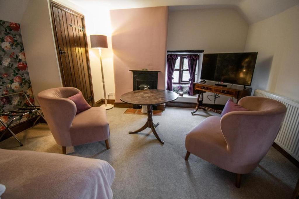 a living room with a table and chairs and a television at The Royal George in Cottingham