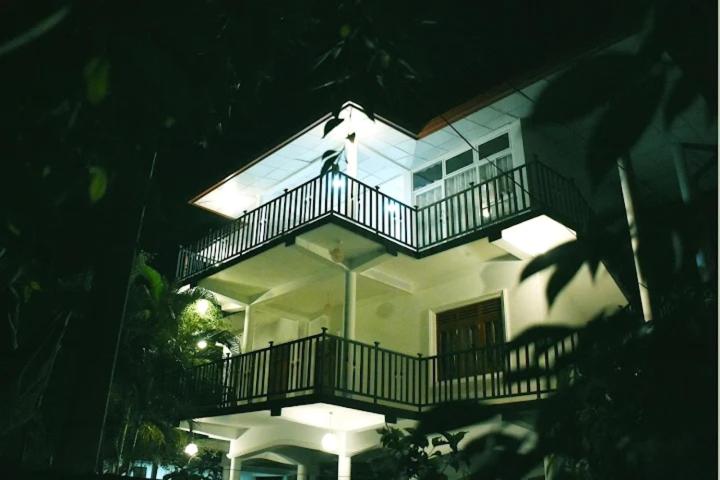 a large white house with a balcony with lights at Royal Inside Hotel in Udawalawe