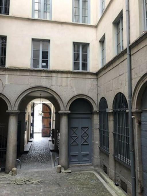a building with arches and a door in a courtyard at Le petit Opéra in Lyon