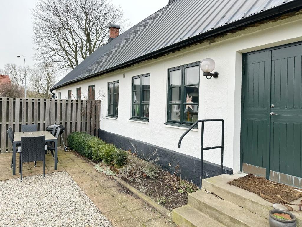 ein weißes Haus mit einer grünen Tür und einem Tisch in der Unterkunft Kåseberga Byhus in Ystad