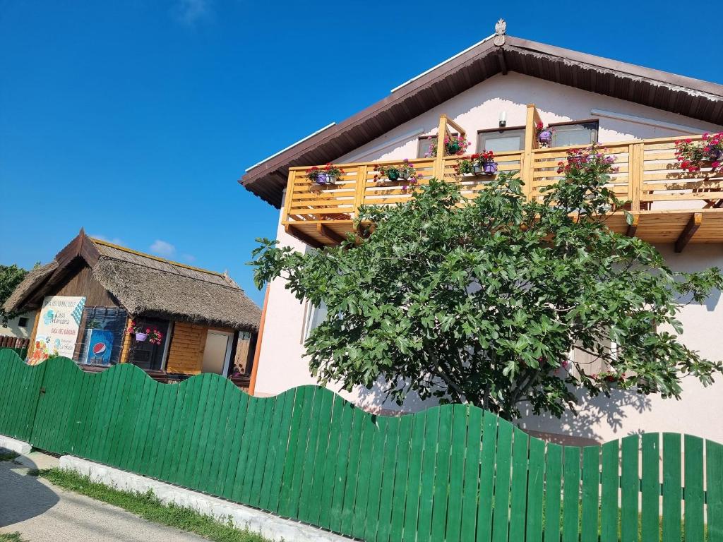 una casa con una recinzione verde e un albero di CASA MOREANA a Sfântu Gheorghe