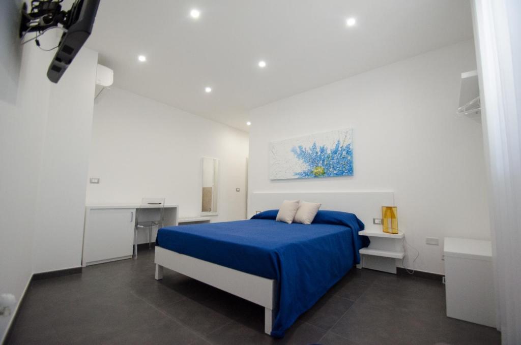 Un dormitorio blanco con una cama azul y una pintura en Sea Salt, en Porto Cesareo