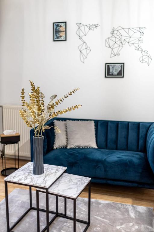 a blue couch in a living room with a table at Le CosyNaï - 20min to Paris in Sannois