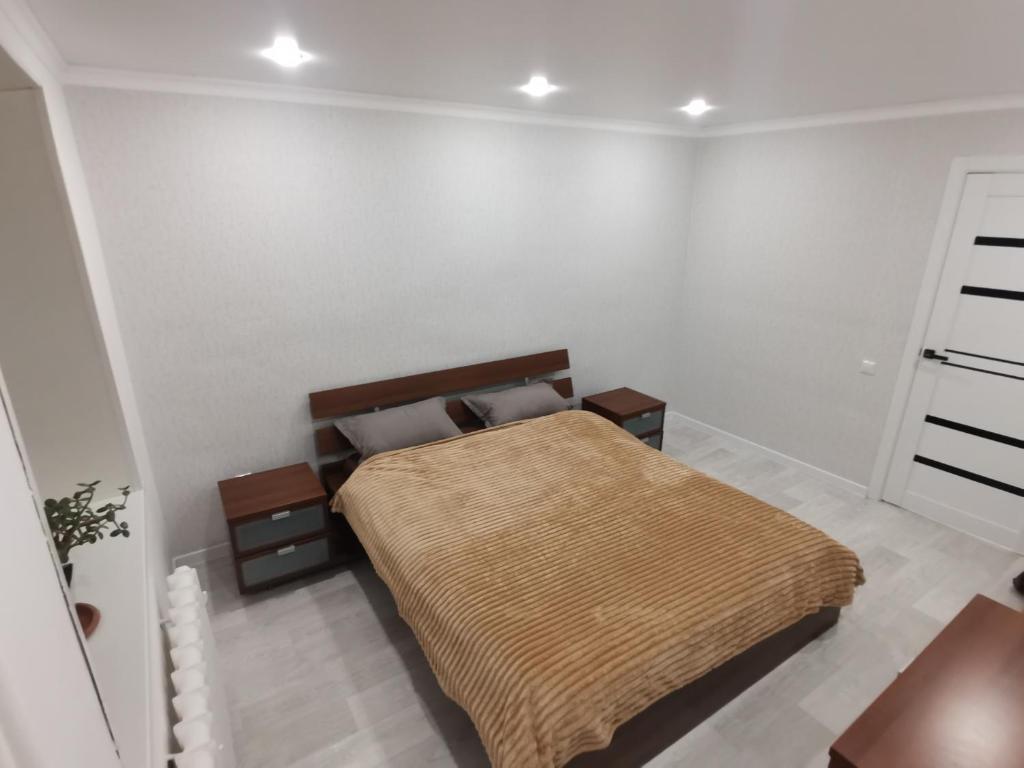 a bedroom with a bed with a brown blanket at Уютные 2х комнатные апартаменты на юбилейной in Uralsk