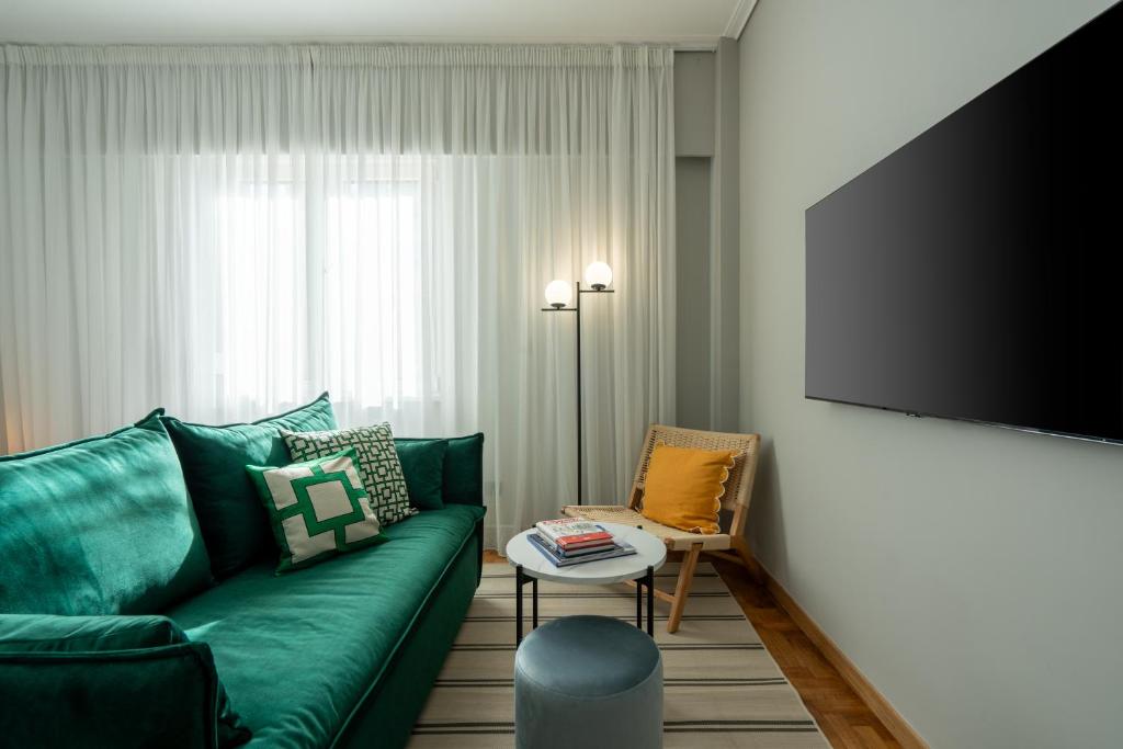 a living room with a green couch and a flat screen tv at Syntagma Bliss: Athens Hub in Athens