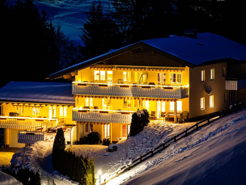 una casa con luces encendidas en la nieve por la noche en Landhaus Harmonie, en Riezlern
