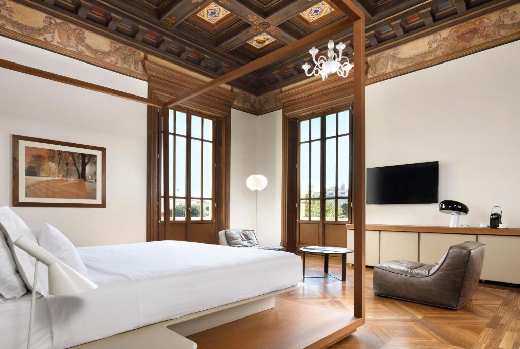 um quarto com uma grande cama branca e uma secretária em Palazzo Montemartini Rome, A Radisson Collection Hotel em Roma