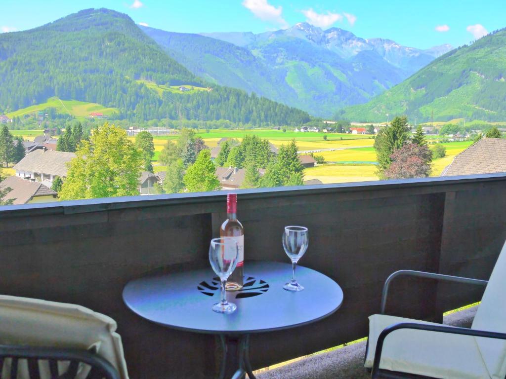 una mesa con dos copas y una botella de vino en Spacious Apartment in HausBellevue with Balcony and Panoramic Mountain Aspect, en Sankt Michael im Lungau