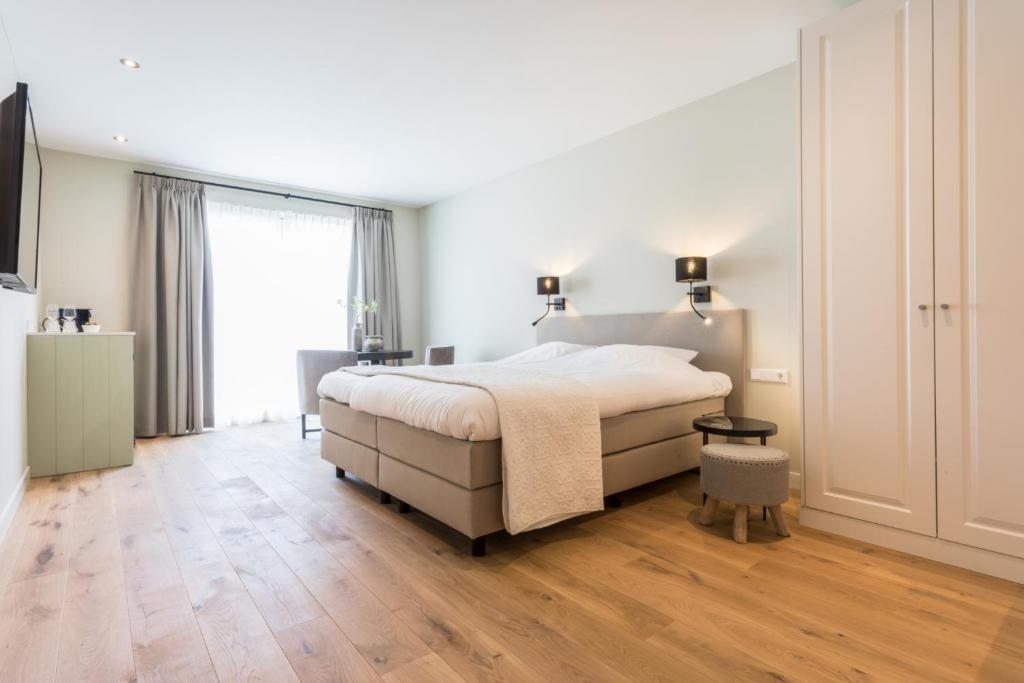 um quarto com uma cama grande e piso em madeira em Zeayou Zeeland - Studio's Zuidstraat 1 em Domburg