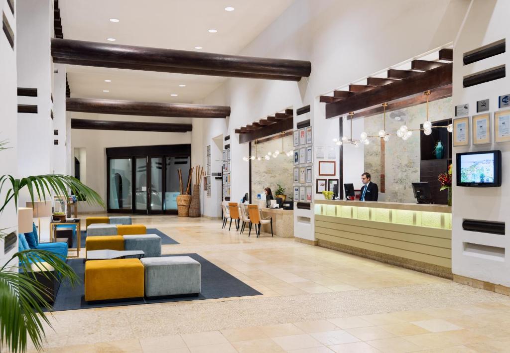 a lobby with a restaurant with yellow and blue chairs at H10 Estepona Palace in Estepona
