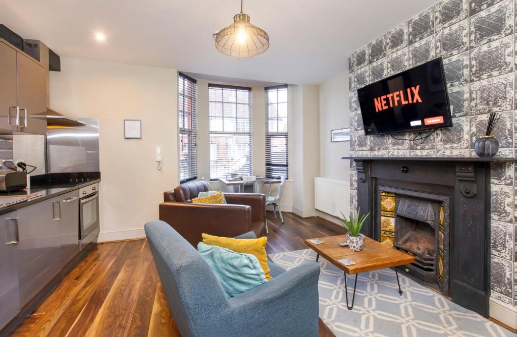 a living room with a fireplace and a kitchen at Clearly Apartments Bootham York in York