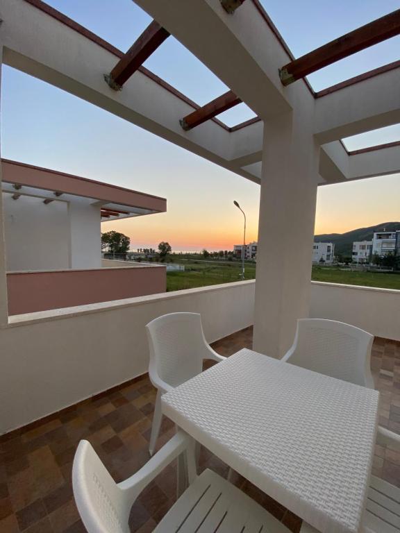 una mesa blanca y sillas en un balcón con vistas a la puesta de sol en Tea Residence, Gjiri i Lalzit Apartments en Durrës
